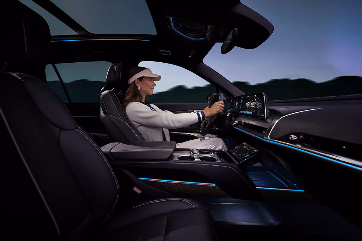 Interior del Cadillac VISTIQ 2026, conductora disfruta iluminación ambiental y doble pantalla panorámica con tecnología premium de infoentretenimiento