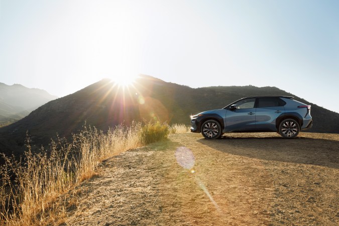 Subaru Uncharted 2027 azul sobre tierra, SUV eléctrico robusto preparado para aventura, iluminación LED encendida bajo cielo nublado.