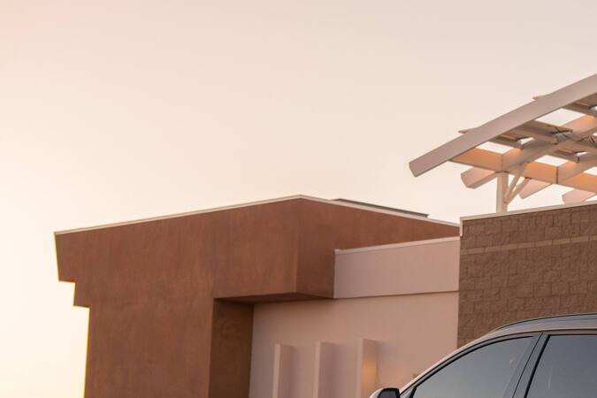 Kia Niro 2027 beige visto desde atrás estacionado al atardecer, detalle de luces y diseño trasero.