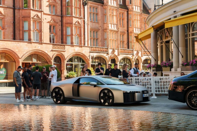 Audi Nuvolari en exhibición frente a edificio histórico con público. Concept car premium de alto rendimiento en entorno urbano elegante.