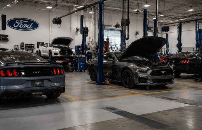 Taller de servicio Ford con varios Mustang en revisión mecánica por recall.