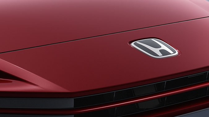 Primer plano del frontal del Honda Prelude rojo con logo Honda y placa Prelude en detalle premium.