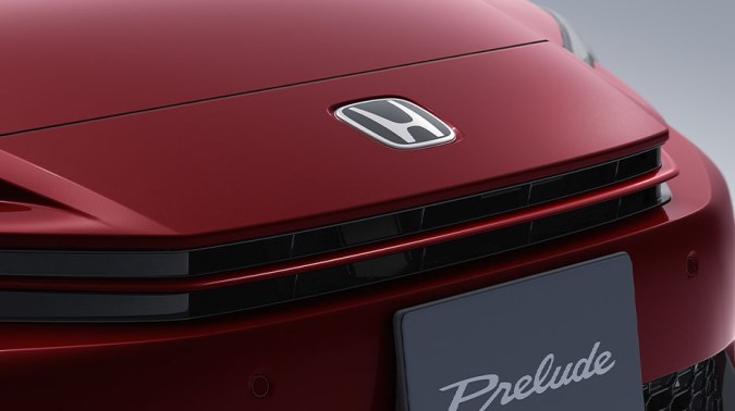 Primer plano del frontal del Honda Prelude rojo con logo Honda y placa Prelude en detalle premium.