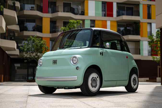 Fiat Topolino eléctrico verde pastel aparcado en ciudad, microcar urbano compacto ideal para movilidad sostenible en espacios reducidos.