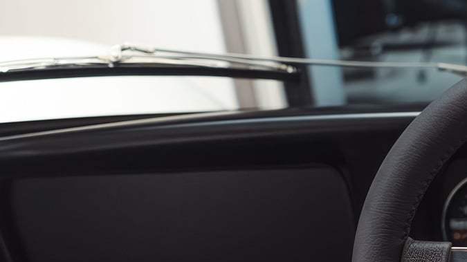 Cabina del McLaren M6GT con volante clásico, tablero analógico y tapicería verde, interior minimalista de carreras