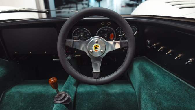 Cabina del McLaren M6GT con volante clásico, tablero analógico y tapicería verde, interior minimalista de carreras
