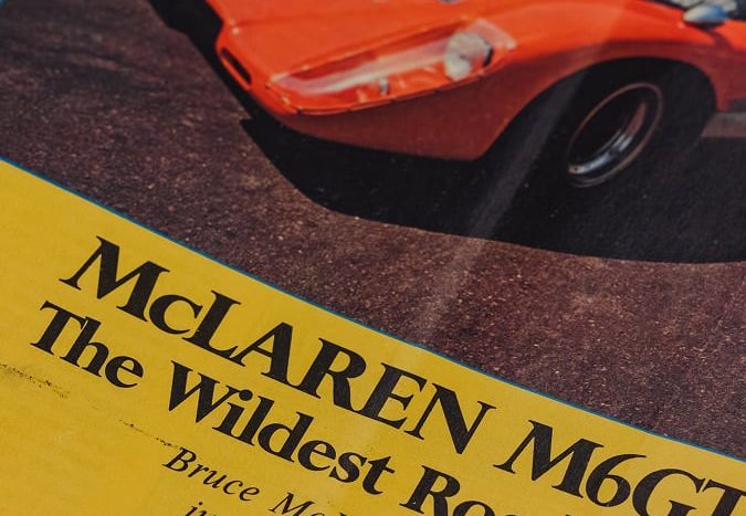 Revista vintage con portada dedicada al McLaren M6GT, el ‘wildest road car’, texto y foto del deportivo naranja.