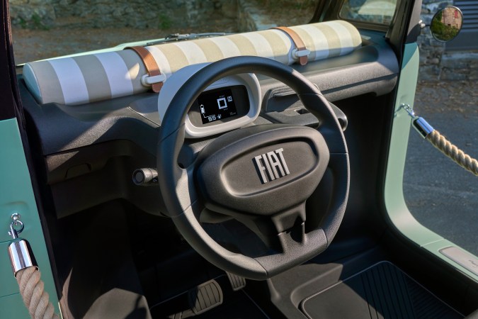 Interior del Fiat Topolino Dolcevita, volante minimalista y cuadro digital compacto, diseño sencillo para conducción urbana en microcar eléctrico.