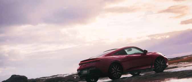 Vista trasera tres cuartos del Honda Prelude rojo en paisaje costero al atardecer, diseño deportivo.