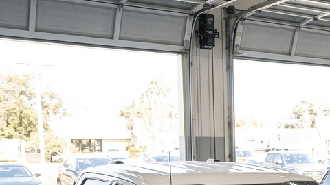 Un técnico de servicio inspecciona varios vehículos Ford y Lincoln dentro de un taller de reparaciones, con carteles de 'Campaña de Retirada de Seguridad'.