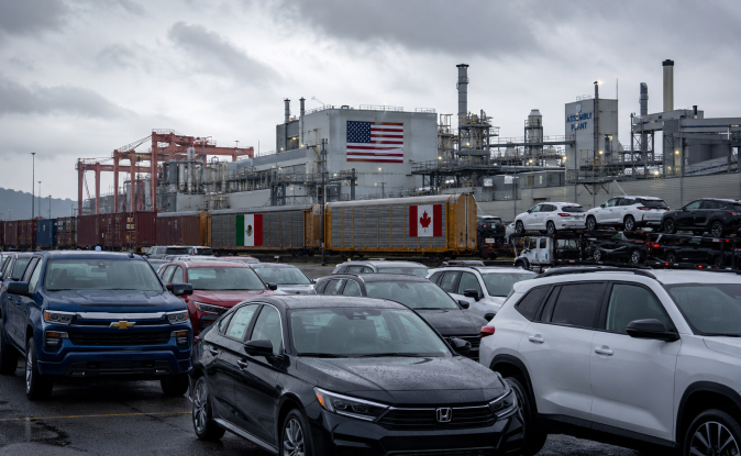 Planta automotriz T-MEC con banderas de México, Estados Unidos y Canadá. Cadena de producción integrada de autos en Norteamérica.