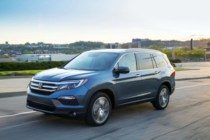 Honda Pilot azul en movimiento, SUV familiar espaciosa con tres filas de asientos.