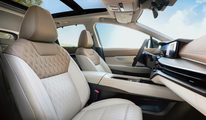 Interior del Nissan Murano 2027 con asientos de cuero color beige, techo panorámico y pantalla táctil central.