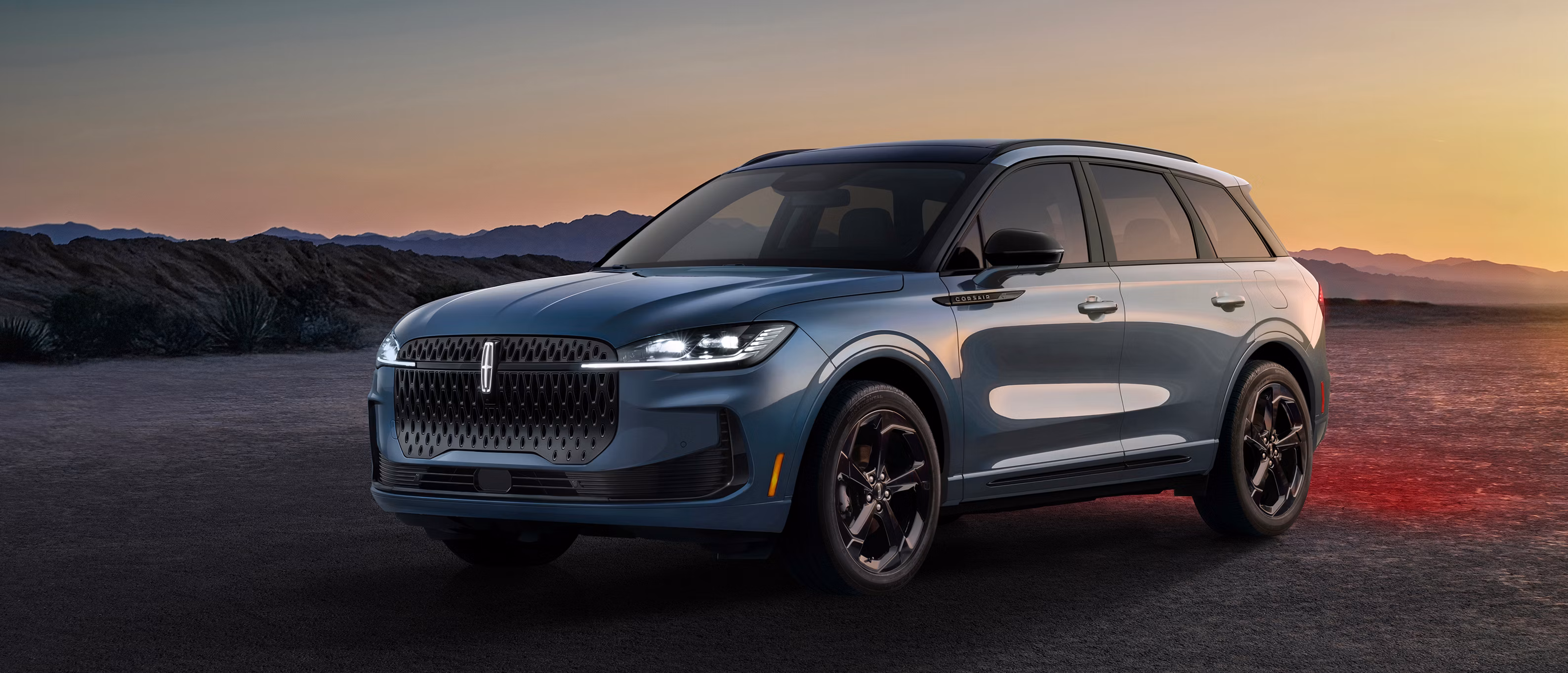 Lincoln Corsair 2027 azul visto de frente durante el atardecer, con parrilla distintiva y faros LED encendidos.