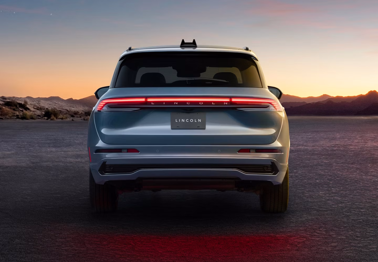 Lincoln Corsair 2027 visto desde atrás al atardecer, con luces LED encendidas y paisaje montañoso.
