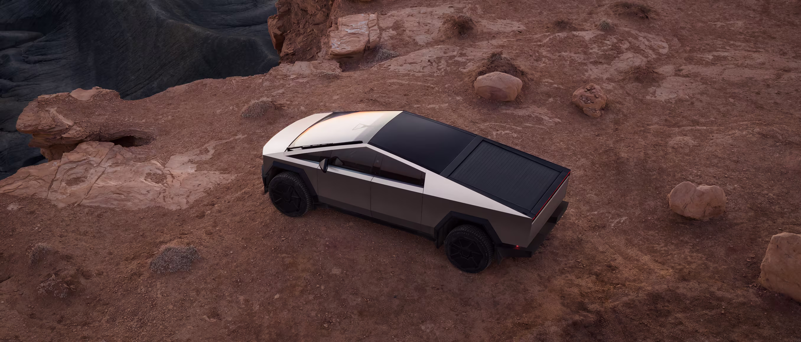 Tesla Cybertruck blanco y negro estacionado en un terreno rocoso del desierto.