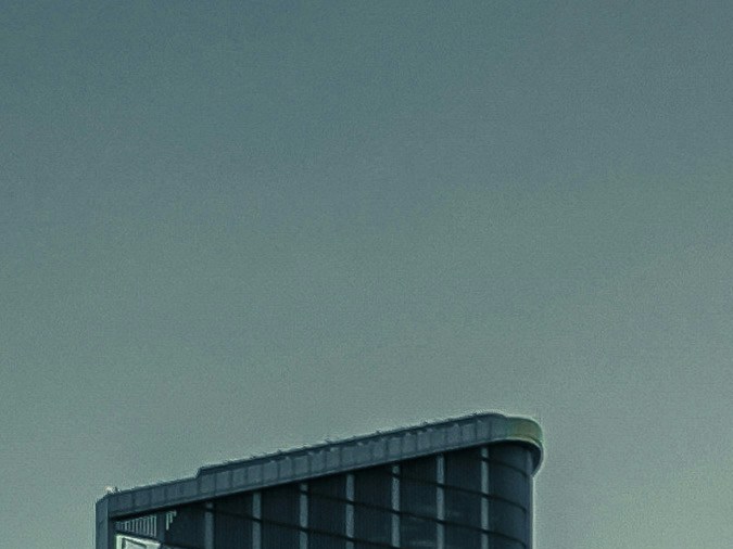 Vista urbana de una ciudad estadounidense con edificios históricos, tráfico vehicular y torre corporativa al atardecer.