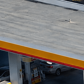Vista aérea de gasolinera Shell y Circle K con varios autos estacionados junto a las bombas.