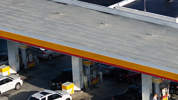 Vista aérea de gasolinera Shell y Circle K con varios autos estacionados junto a las bombas.