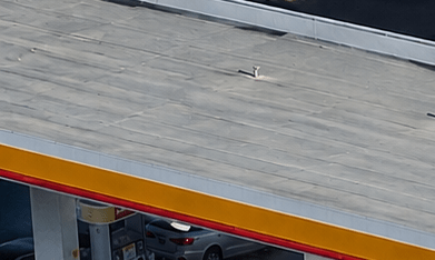 Vista aérea de gasolinera Shell y Circle K con varios autos estacionados junto a las bombas.