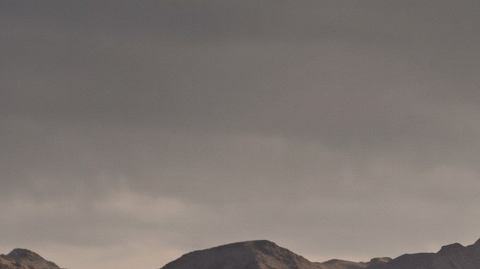 Cinco vehículos todoterreno de distintas marcas, incluyendo Tesla Cybertruck y Jeep Wrangler, avanzan en formación por un desierto árido al atardecer.