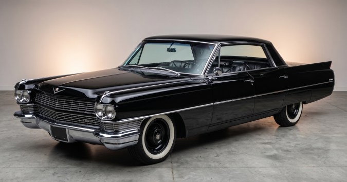 Cadillac Series 62 negro clásico con carrocería brillante, cromados y neumáticos de banda blanca.