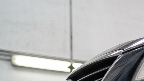 Mecánico inspecciona la suspensión y el sistema de frenos de un auto usado elevado en un taller.