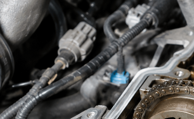 Motor con árbol de levas y cadena de distribución expuestos para diagnosticar vibraciones y fallas mecánicas en el carro.