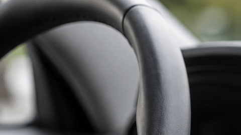 Interior de un auto moderno con una pantalla táctil de infoentretenimiento, mientras un conductor interactúa con el sistema multimedia desde el asiento del conductor.