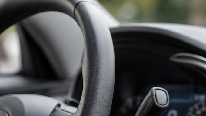 Interior de un auto moderno con una pantalla táctil de infoentretenimiento, mientras un conductor interactúa con el sistema multimedia desde el asiento del conductor.