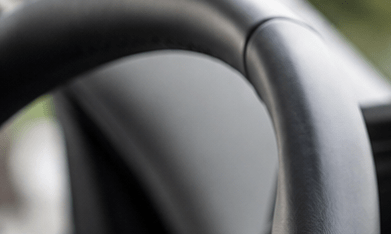 Interior de un auto moderno con una pantalla táctil de infoentretenimiento, mientras un conductor interactúa con el sistema multimedia desde el asiento del conductor.