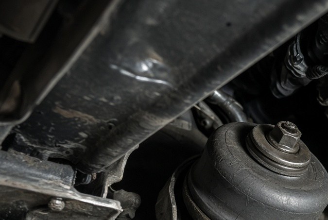 Soporte de motor dañado bajo el chasis del carro, posible causa de vibración fuerte al poner la transmisión en Drive.