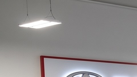 Un taller de servicio autorizado de Toyota con múltiples elevadores hidráulicos que sostienen camionetas y SUVs blancas, negras y rojas para mantenimiento y reparación.
