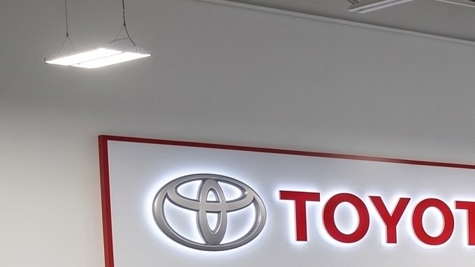 Un taller de servicio autorizado de Toyota con múltiples elevadores hidráulicos que sostienen camionetas y SUVs blancas, negras y rojas para mantenimiento y reparación.