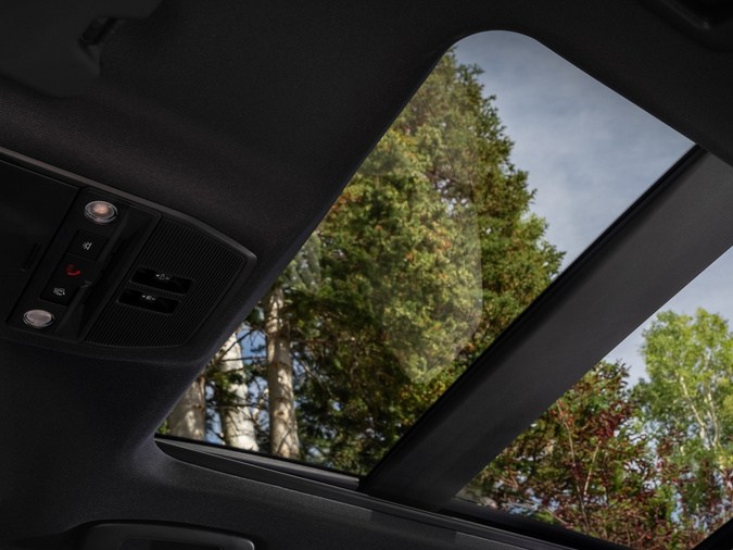 Techo corredizo panorámico de la camioneta SUV Nissan Rogue Hybrid con asientos de cuero blanco y vista al cielo.