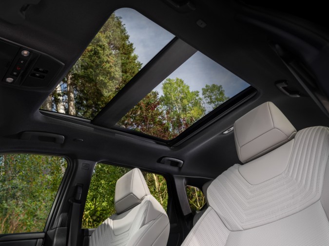 Techo corredizo panorámico de la camioneta SUV Nissan Rogue Hybrid con asientos de cuero blanco y vista al cielo.