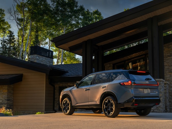 Vista trasera de la Nissan Rogue Hybrid mostrando su diseño aerodinámico, luces traseras conectadas y rines bitono.