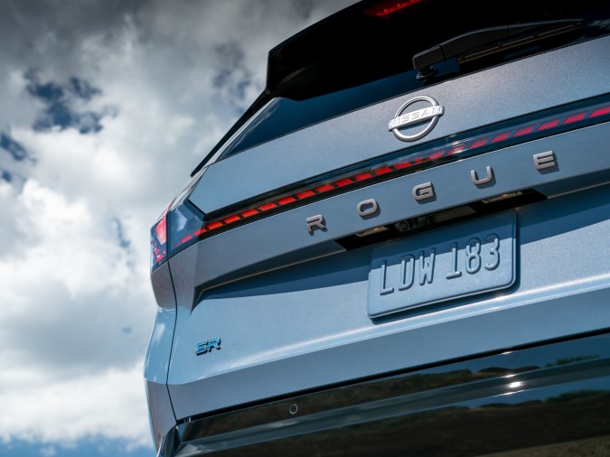 Detalle de la compuerta trasera de Nissan Rogue SR Hybrid con emblema cromado y barra de luces LED.