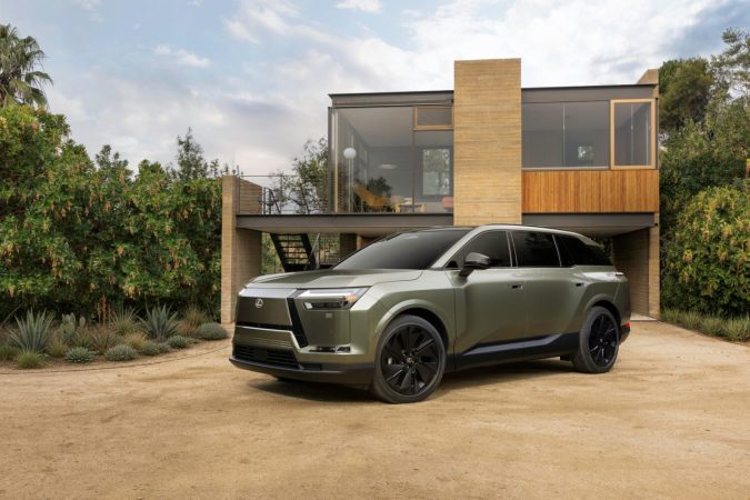 Lexus TZ 2027 SUV verde oliva estacionado frente a residencia contemporánea de madera y cristal.