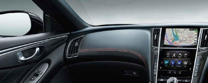 Interior deportivo del Nissan Skyline NISMO con volante multifunción, acabados en fibra de carbono y detalles en costura roja.