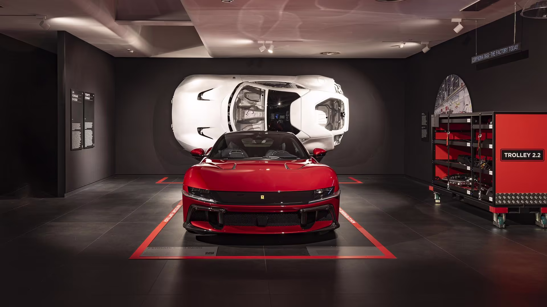 Ferrari Roma rojo exhibido en museo junto a una maqueta blanca durante una exposición sobre innovación automotriz.
