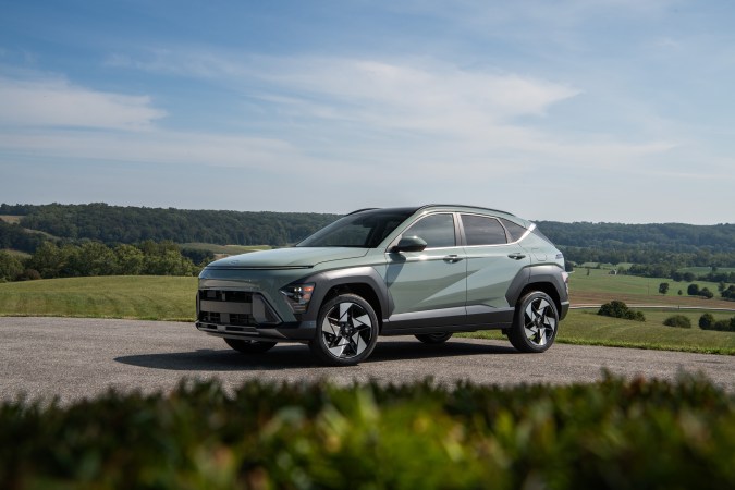 Hyundai Kona 2025 estacionada en una carretera rural, rodeada de campos y colinas.
