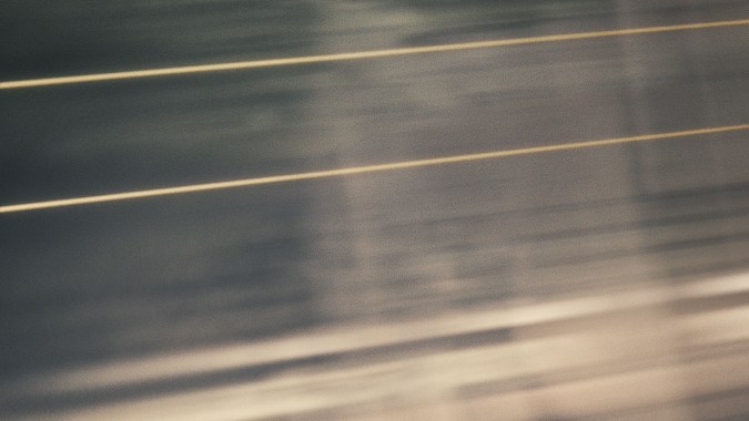 Vista trasera del McLaren Artura negro con marcado 1000 GP circulando a alta velocidad.