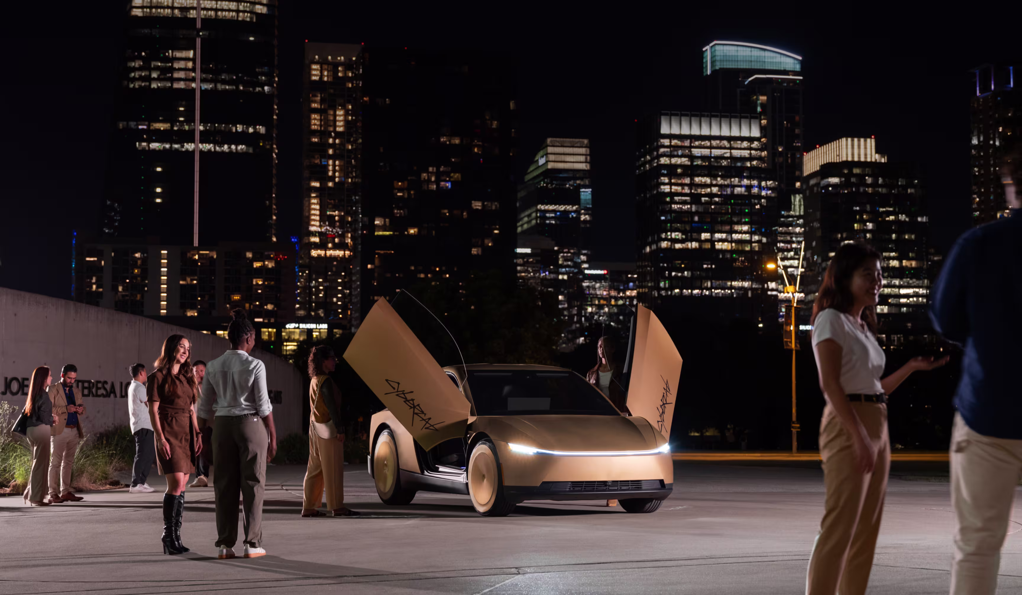 Tesla Cybercab dorado con puertas abiertas junto a un grupo de personas y edificios iluminados durante la noche.