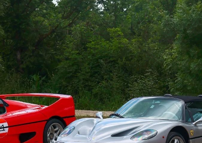 Espectacular auto deportivo clásico Ferrari F50 color gris plata estacionado al aire libre, acompañado de otros icónicos modelos Ferrari rojos.