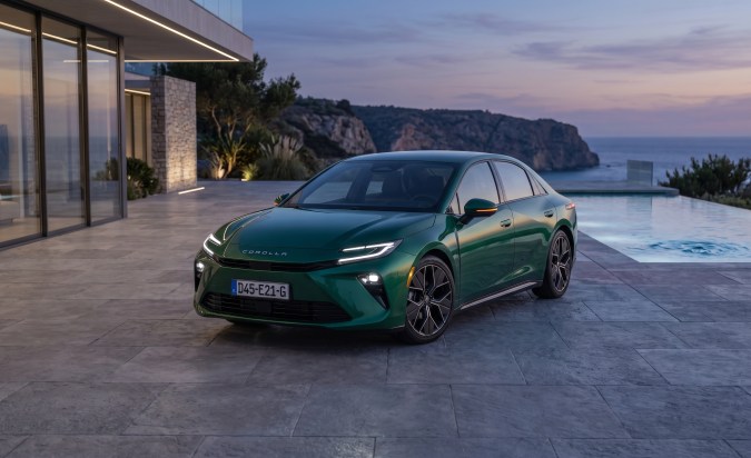 Toyota Corolla 2028 verde estacionado frente a villa moderna con piscina y vistas al mar al atardecer.