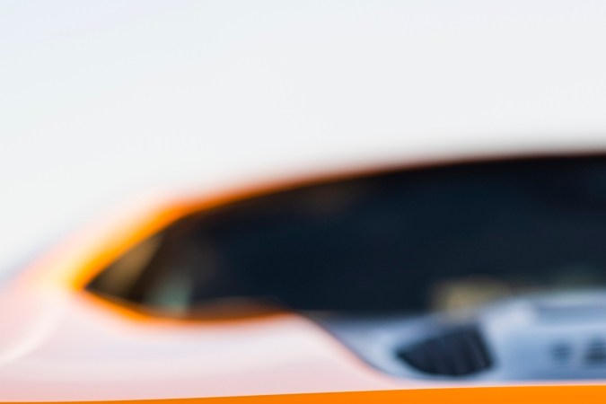 Detalle trasero del McLaren Artura naranja con escape doble, parrilla hexagonal y logo McLaren Artura.
