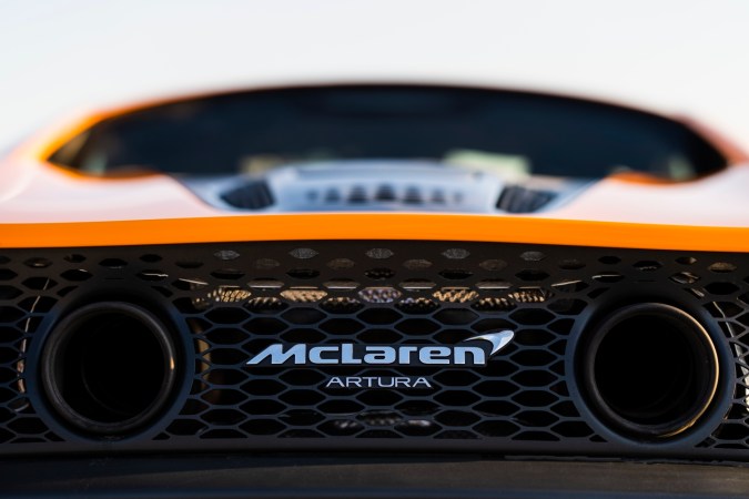 Detalle trasero del McLaren Artura naranja con escape doble, parrilla hexagonal y logo McLaren Artura.