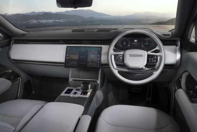 Interior del Range Rover eléctrico con pantalla táctil, volante multifunción y tablero digital minimalista.
