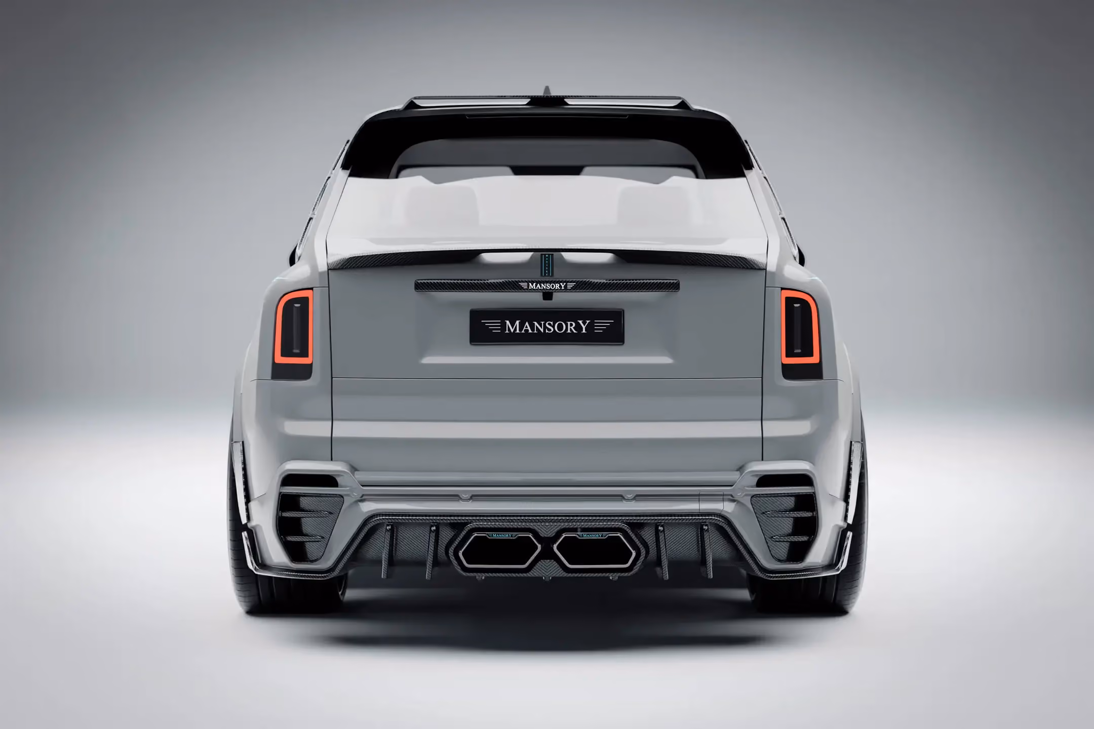 Rolls-Royce Cullinan Mansory blanco visto desde atrás, con difusor deportivo, escapes dobles y detalles en fibra de carbono.